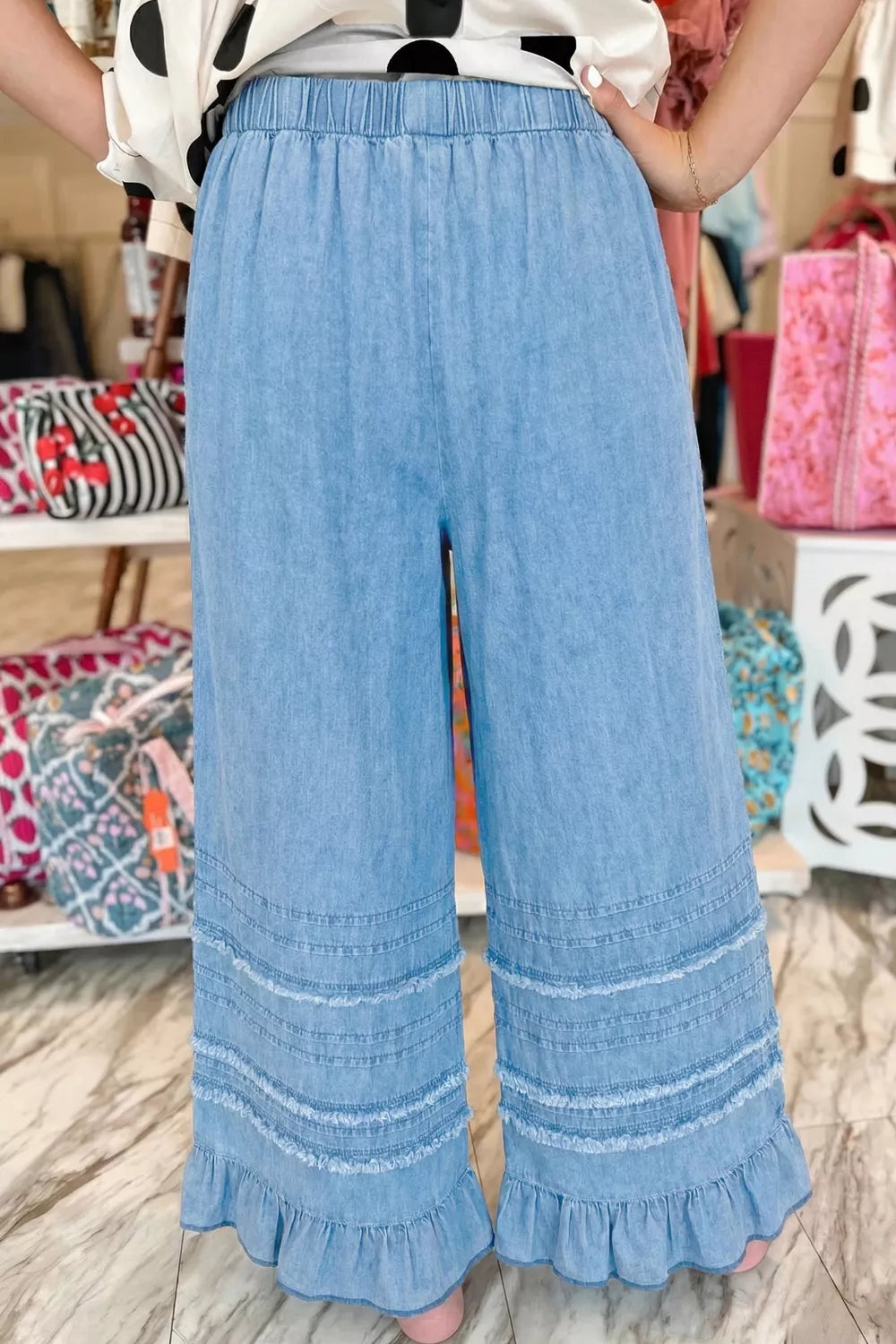 Ruffled hem detail on light blue chambray jeans