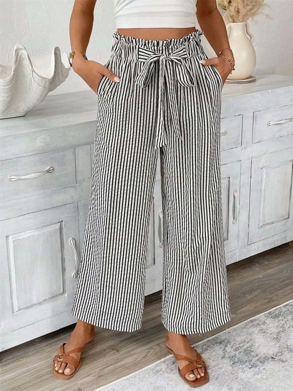 Woman wearing black wide leg paper bag pants front view