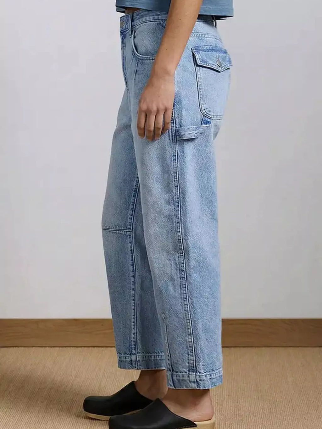 Button closure and waistband detail on washed blue jeans