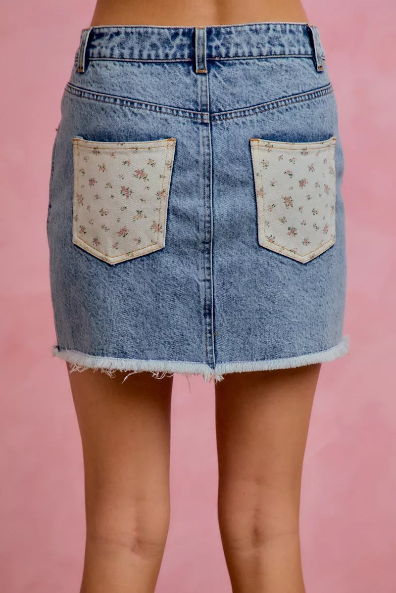 Close up of floral print on washed denim skirt